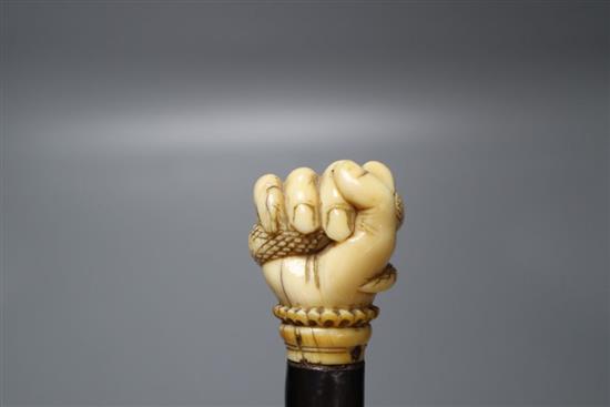 An ebonised walking cane, the handle of a carved ivory hand holding a coiled serpent, length 87cm
